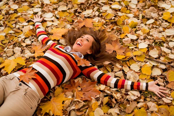 Femme couchée sur le sol couverte de feuilles — Photo