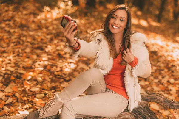 Mujer sonriente tomando selfie en el bosque — Foto de Stock