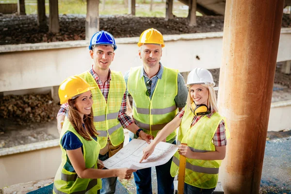 Four construction architects review plan — Stock Photo, Image