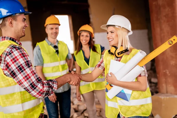 Architects shaking hands in damaged building — Stock Photo, Image