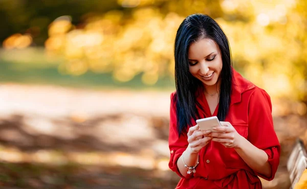 Kvinna med mobiltelefon i park — Stockfoto