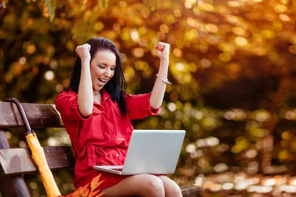 Gelukkige vrouw met laptop zit op bankje — Stockfoto