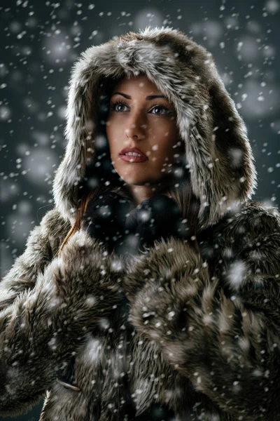 Γυναίκα στο παλτό που στέκεται μεταξύ νιφάδες χιονιού — Φωτογραφία Αρχείου