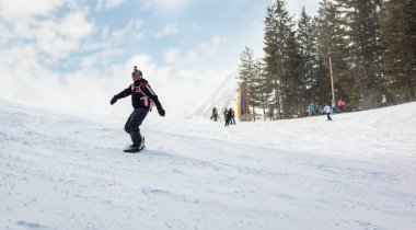Genç adam snowboard ve dağ yamaçlarında bir güneşli kış günü zevk sürmek.