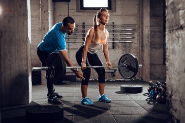 Genç kadının kişisel bir eğitmen ile spor salonunda çapraz uygun egzersiz yapması.