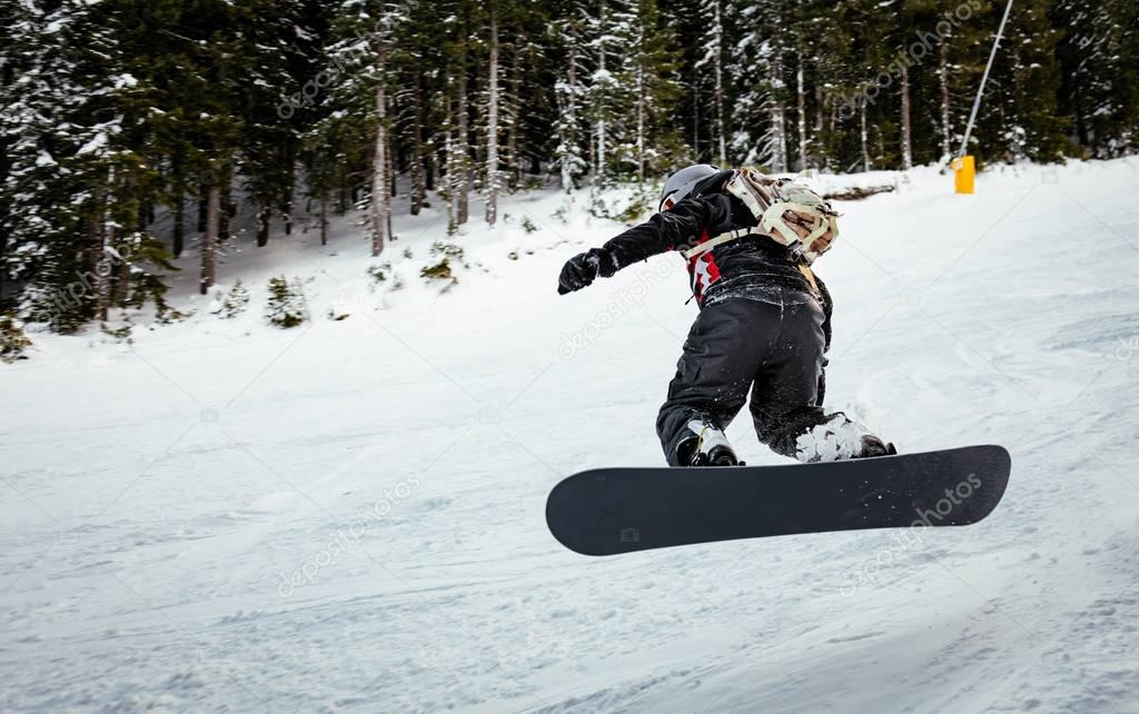 Snowboarder jumps on mountain slopes and enjoying a frozen winter day.