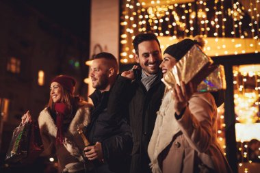 Şehrin ışıkları arka plan üzerinde bir sürü sokak yılbaşı geceleri eğlenmeye genç üç çift.