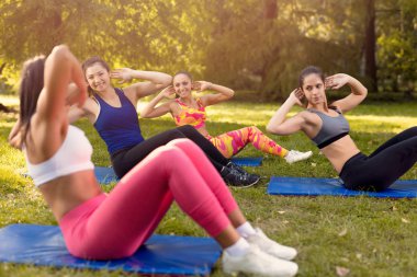 Güzel kız sit-up Park kadın fitness eğitmeni ile yapıyor. Seçici odak.