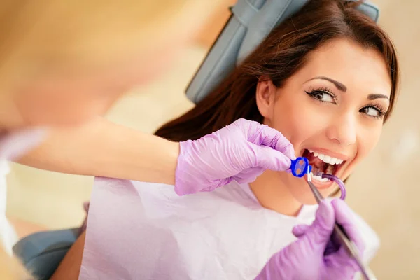 歯科医のオフィスでの美しい若い女性をご覧ください 彼女は彼女の歯を修理椅子と歯科医に座ってください 選択と集中 — ストック写真
