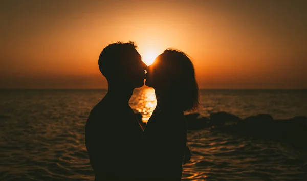 一对相爱的情侣在海滩上拥抱和亲吻日落的剪影 — 图库照片