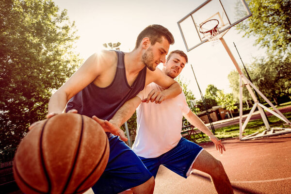 Two street basketball players playing one on one. They are making a good action and guarding the ball.