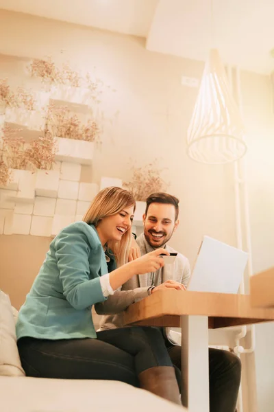 年轻美丽的微笑夫妇坐在咖啡馆和网上购物的笔记本电脑上 — 图库照片