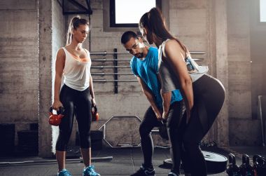 Spor salonunda kişisel bir eğitmen ile egzersiz iki kız arkadaşım.