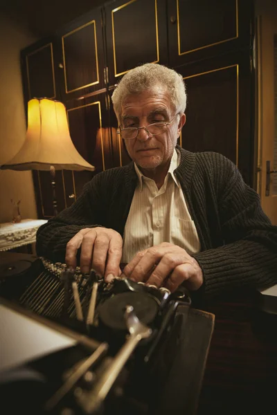 古いタイプライターで書くメガネ レトロなシニア男性作家 — ストック写真