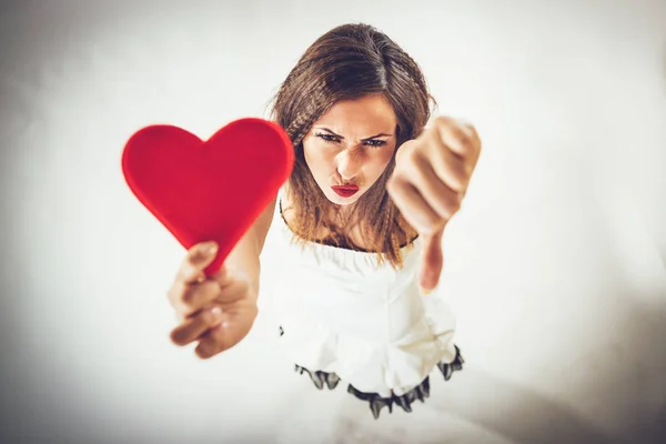 美丽的不满女孩抱着红色的心 指着拇指下来 情人节概念 — 图库照片