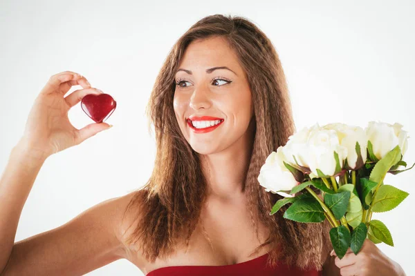 一个美丽的微笑女孩的肖像捧着一颗红色的心和一束白色的玫瑰花 — 图库照片