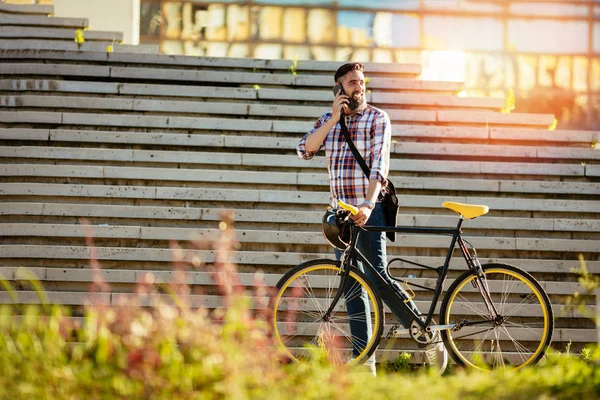 カジュアルなビジネスマンは自転車で仕事に行きます 彼は自転車を押して 電話を使用して — ストック写真
