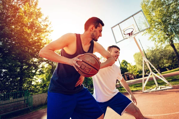 Two street basketball players playing one on one. They are making a good action and guarding the ball.
