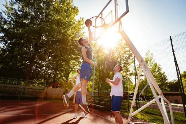 年轻的篮球运动员在街头球场进行训练 他们在一起玩耍和行动 年轻人投掷球到圆环 — 图库照片
