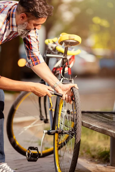 都会の人間が路上で自転車の車輪をポンプ — ストック写真