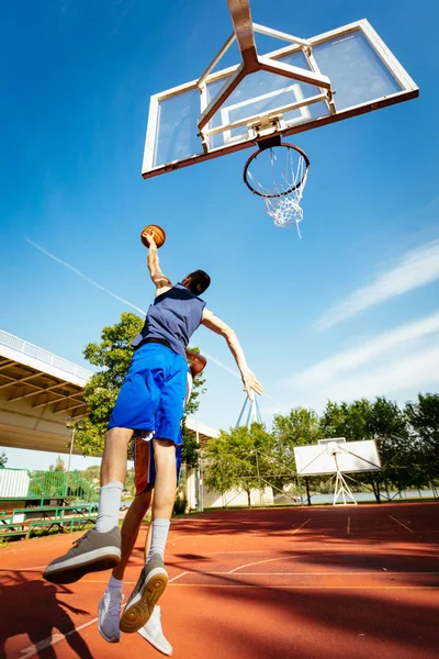 Two street basketball players having training outdoor. They are making a good action.