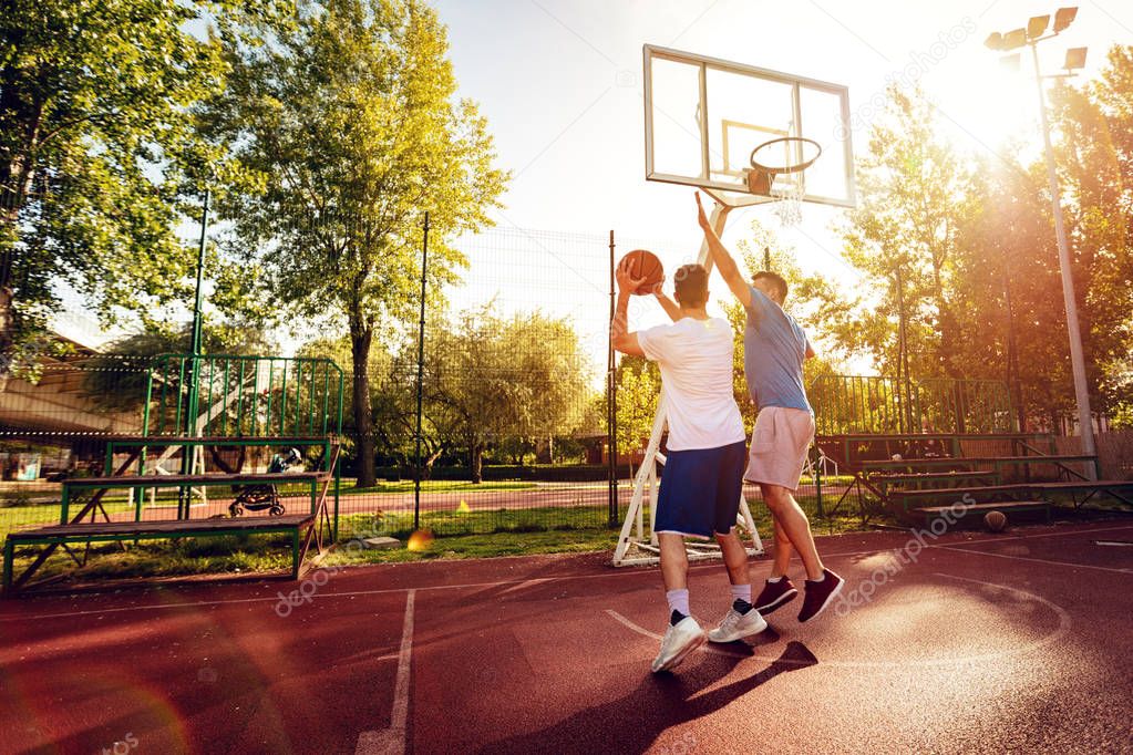 Two street basketball players having training outdoor. They are making a good action.