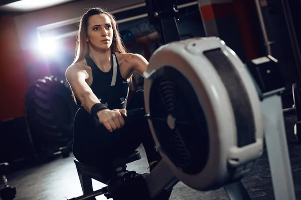 Woman pulling the rowing machine — Stock Photo, Image