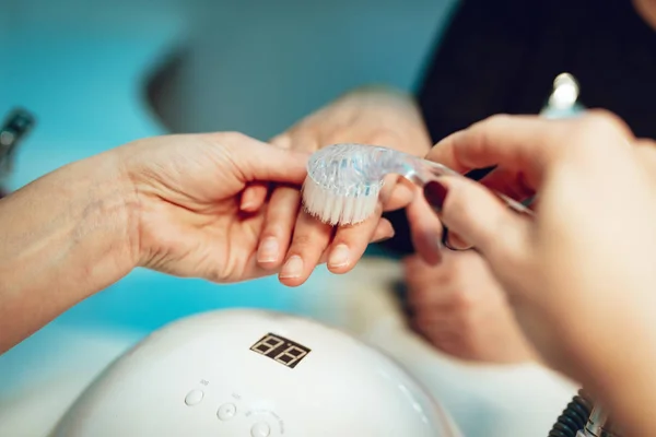 Esthéticienne brossant les ongles féminins — Photo