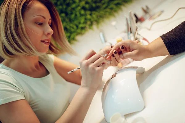 Schoonheidsspecialiste lakken van de nagels voor vrouwelijke client — Stockfoto