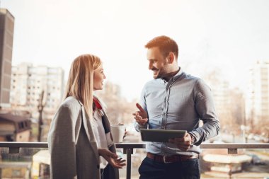 Kahve molası verdikten ve ofis önünde balkonda dijital tablet kullanarak girişimci gülümseyen genç.