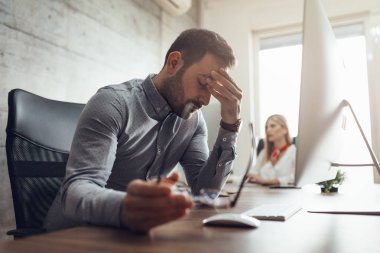 Genç yakışıklı sinirli ve office bilgisayar önünde oturan ve kafa tutan işadamı vurguladı.