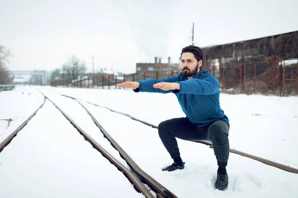 アクティブな若い男とやって身をかがめる演習訓練外冬の間に古い鉄道の間で公共の場所 — ストック写真