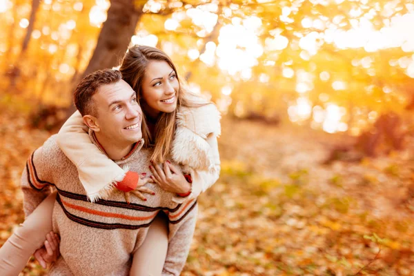 美丽的年轻夫妇享受搭载在阳光森林在秋天的颜色 — 图库照片
