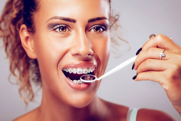 Sorrindo Jovem Mulher Verificando Aparelhos Com Espelho Dental — Fotografia de Stock