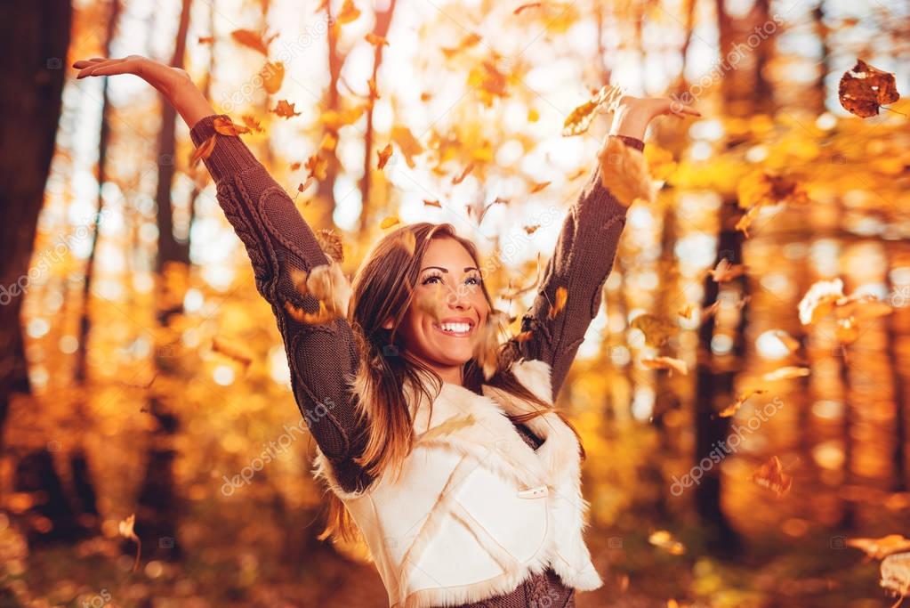 Cheerful young woman having fun in sunny forest in autumn colors.