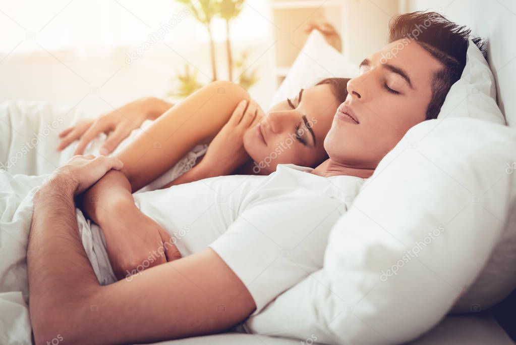 Romantic hugging young couple sleeping in bed. 