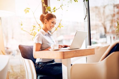 Cafe 'de dizüstü bilgisayarda çalışan genç bir kadın.