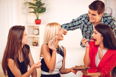 Kanepede oturan ve doğum günü pastası yemek genç arkadaş grubu