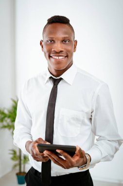 Dijital tablet tutarak ve kameraya bakarak genç Afrika iş adamı