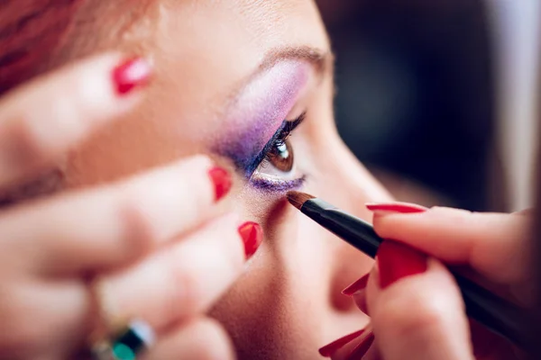 Makeup artist applying the eyeshadow to model