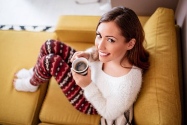 oturma odasında kanepede oturan ve kahve içme genç esmer kadın