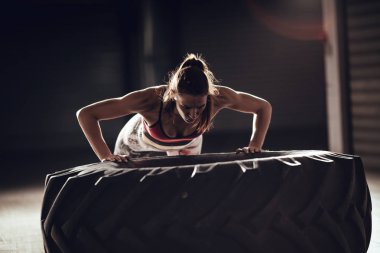 Crossfit eğitim, lastik üzerinde push-up egzersiz yaparak genç kaslı kadın