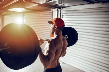 Genç kaslı adam yüksek çekme egzersiz halter ile çapraz eğitim saatinde