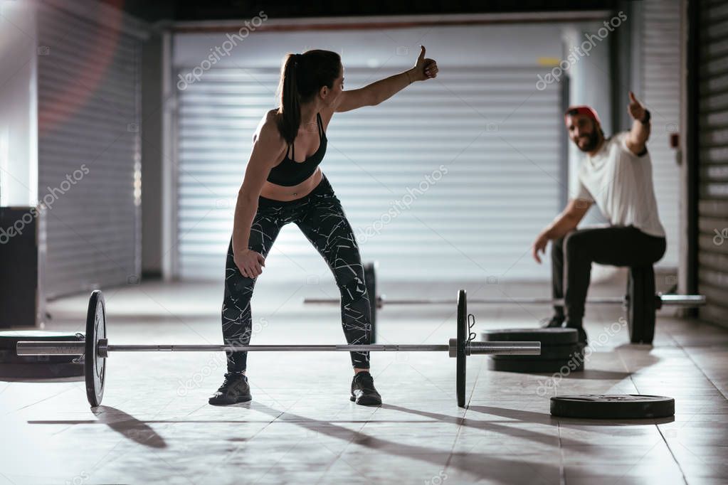 Young muscular couple lifting barbell on cross training