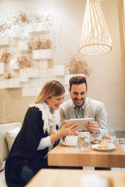 Genç bir çift söz ve sosyal medya dijital tablet kahve molası kafede üzerinde kontrol