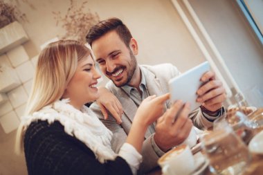 Genç bir çift söz ve sosyal medya dijital tablet kahve molası kafede üzerinde kontrol