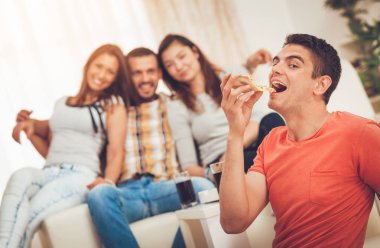 Genç adam oturma ön plan gülümseyen ve pizza yemek