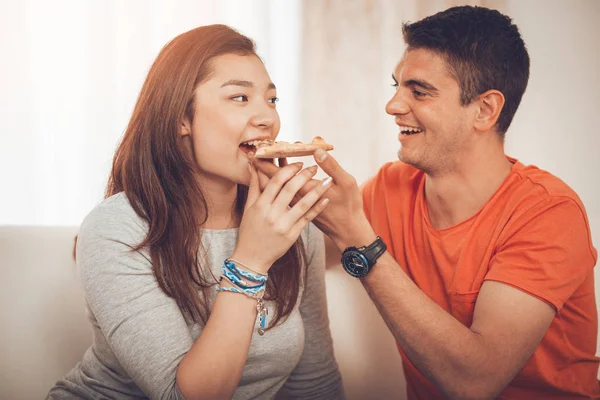 young smiling couple sharing pizza at home