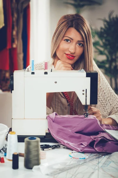 在裁缝编制中与缝纫机和其他缝纫用品一起工作的年轻妇女 — 图库照片