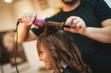 Erkek Kuaför uzun kahverengi saç maşası ile bukleler yapım bir görünümü kapat